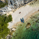 Two kayaks on a pebbly beach with rocky cliffs and clear water.