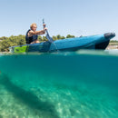 Person kayaking on clear water with a scenic background