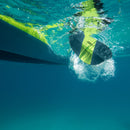 Close-up of a surfboard with a yellow and black design underwater.